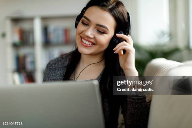 young woman with headphones using laptop at home - office space movie stock pictures, royalty-free photos & images