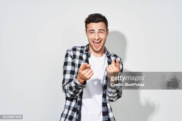 cheerful young man points his fingers at the camera and smiles broadly on a blank white background. - eccitazione foto e immagini stock