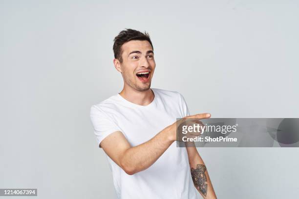 on a happy happy man laughs out loud and point to the side on an empty gray background. - happy laugh stockfoto's en -beelden