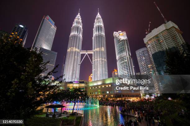 neon illuminated petronas towers at night and klcc park, kuala lumpur, malaysia - menara kuala lumpur tower stockfoto's en -beelden