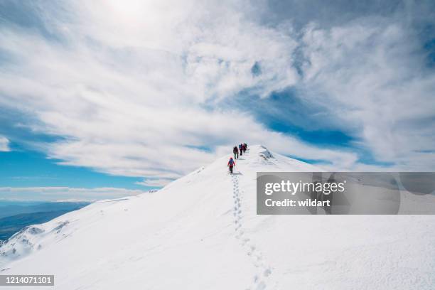 mountain alpine climbing team moving up in a row in high altitude mountain peak in winter - mountain ridge line stock pictures, royalty-free photos & images