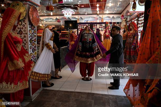 In this picture taken on May 19 a shopkeeper displays a dress on a mannequin as he waits for customers during the government-imposed lockdown as a...