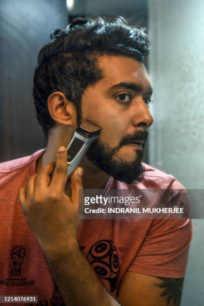 This photo taken on February 6, 2020 shows 30-year-old communications executive Suraj Balakrishnan trimming his beard at his home in Mumbai. -...