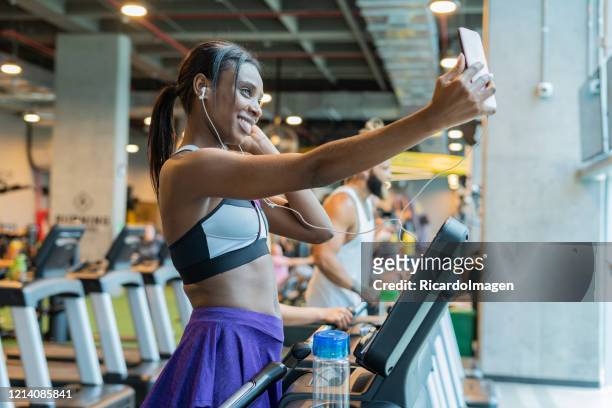 frau macht herz-kreislauf-übung auf einem laufband und sie macht ein selfie - musculoso stock-fotos und bilder