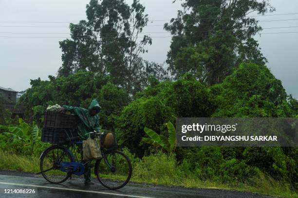 Man pushes a bicycle loaded with vegetable under the rain ahead of the expected landfall of cyclone Amphan in Midnapore, West Bengal, on May 20,...