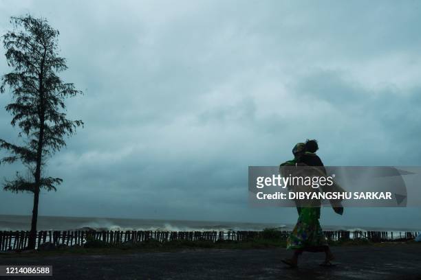 Woman carries her child as she walks along a road near the Tajpur Beach to take shelter ahead of the expected landfall of cyclone Amphan in...