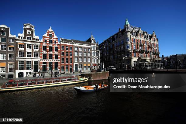 General view on the Singel Canal with people enjoying a boat ride near Koninklijk Paleis or The Royal Palace Amsterdam which will follow national...