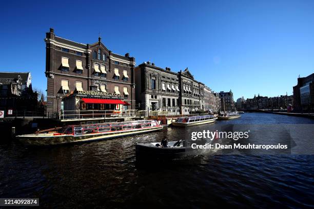 General view on the Singel Canal with people enjoying a boat ride near Koninklijk Paleis or The Royal Palace Amsterdam which will follow national...