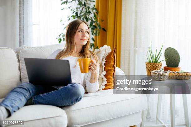 gelukkige glimlachende vrouwenzitting op bank en gebruikend laptop - leisure work coffee happy stockfoto's en -beelden