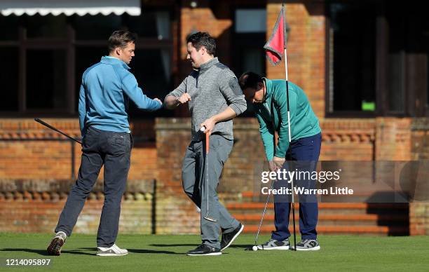 Golfers touch elbows instead of shaking hands as they play at Pine Ridge Golf Club on March 22, 2020 in Camberley, England. Coronavirus has spread to...