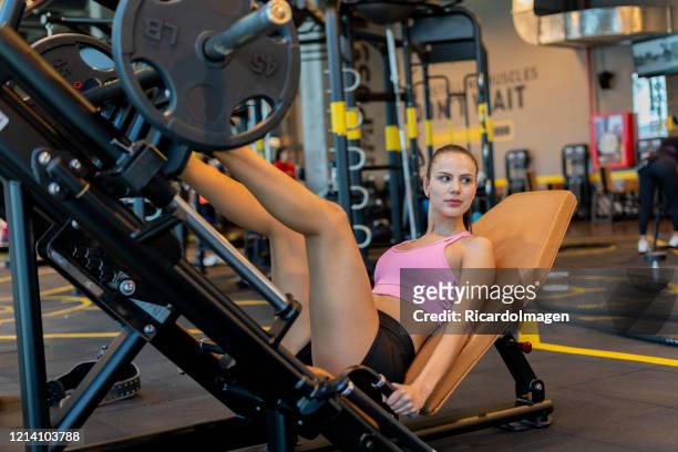 latina woman using leg press in the gym - hispanoamérica stock pictures, royalty-free photos & images