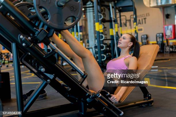 latina woman using leg press in the gym - hispanoamérica stock pictures, royalty-free photos & images
