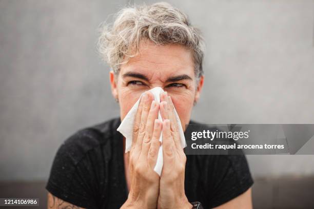 adult woman suffering from spring allergy and blowing a runny nose with a tissue - mucus stock pictures, royalty-free photos & images