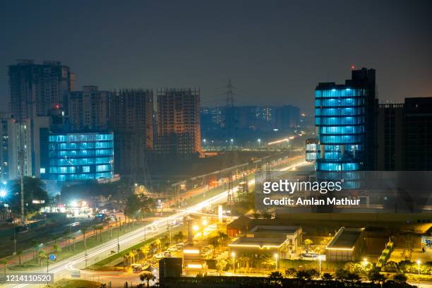 aerial night not of gurgaon with light trails on the road and blue lights on the building - noida photos et images de collection