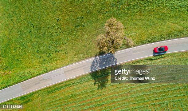 aerial view of  a red convertible car on a country road through agricultural fields - aerial single object stock pictures, royalty-free photos & images