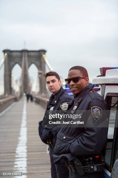 new york city police officers on the brooklyn bridge - new york city police department stock pictures, royalty-free photos & images