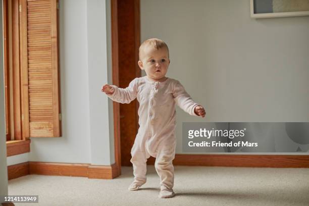 baby first steps walking in bedroom with arms out with good balance - baby walk stock-fotos und bilder