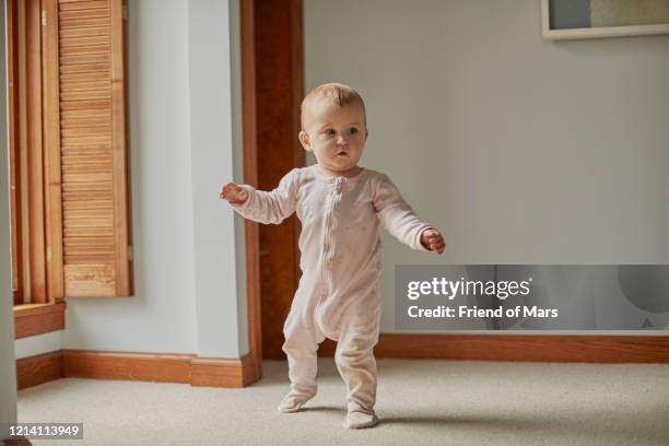 baby first steps walking in bedroom with arms out with good balance - primi passi foto e immagini stock