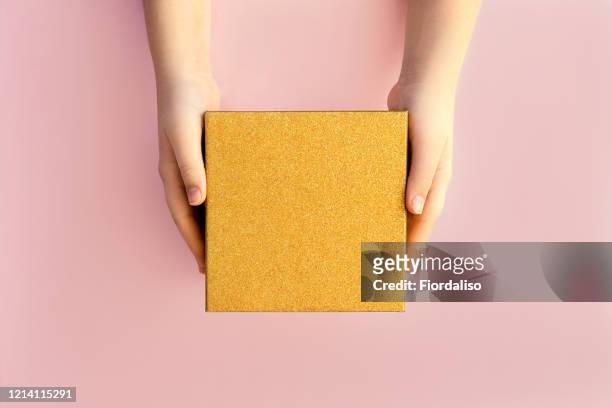 hands of teenage girl holding a golden gift box on pink background - gift box top stock pictures, royalty-free photos & images