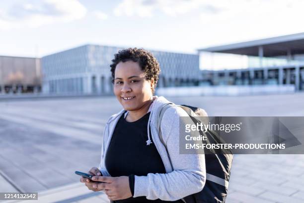 portrait of a young and curvy women with sports bag and mobile phone walking to her fitness club - gym bag stock pictures, royalty-free photos & images