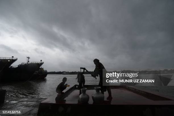 Family collects drinking water froma water pump ahead of the expected landfall of cyclone Amphan, in Khulna on May 20, 2020. - Several million people...