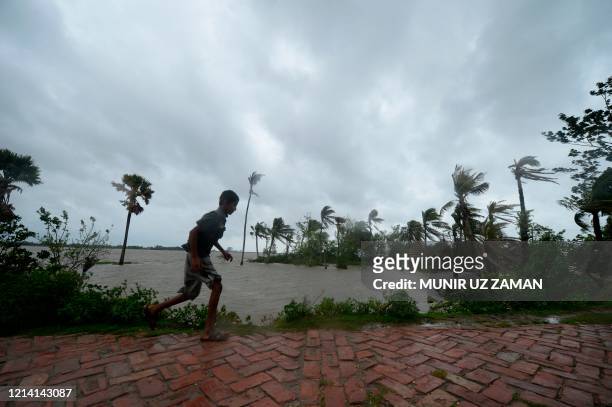 Boy runs along an embankment ahead of the expected landfall of cyclone Amphan, in Dacope on May 20, 2020. - Several million people were taking...