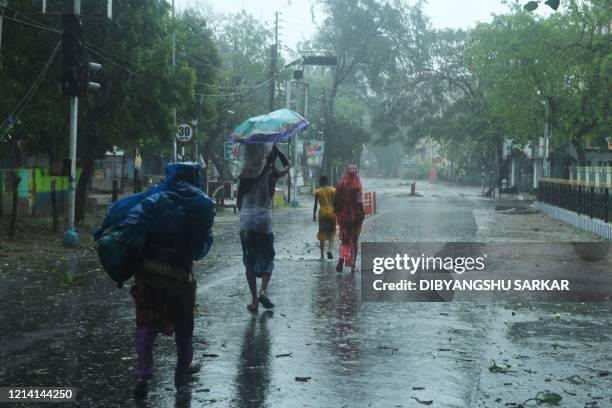 Residents walk along a street to a shelter ahead of the expected landfall of cyclone Amphan in Digha, West Bengal, on May 20, 2020. - India and...