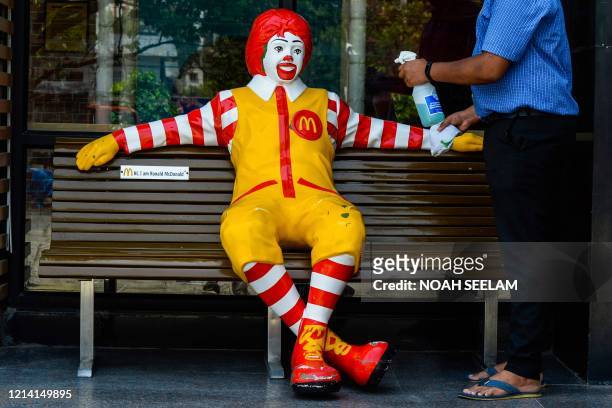 Worker cleans Ronald McDonald, the mascot of fast-food company McDonald's, for the reopening of the outlet after the government eased a nationwide...