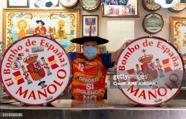 Manuel Caceres Artesero, also known as "Manolo El del Bombo" , poses wearing a face mask in his bar which will close soon as he is due to retire, in...