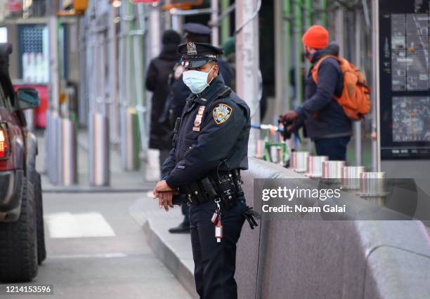 An NYPD police officer wearing a protective face mask is seen in Times Square hours ahead of the implementation of 'New York State on PAUSE'...