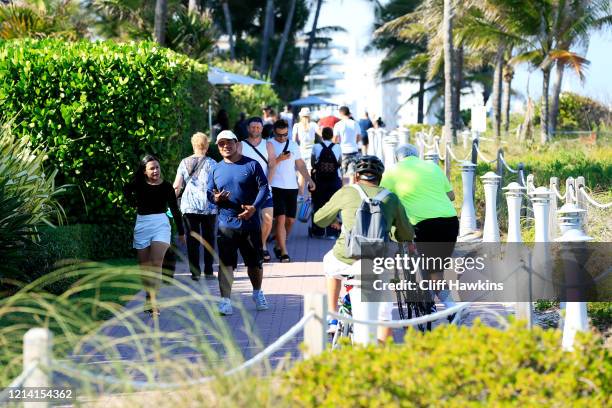 People walk on the boardwalk in the South of Fifth neighborhood on March 22, 2020 in Miami Beach, Florida. The city of Miami Beach has closed all...