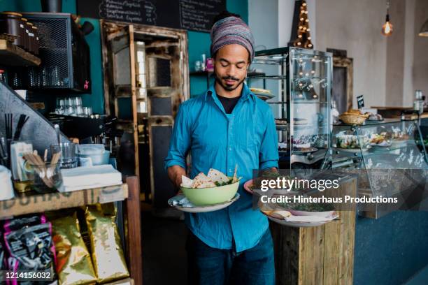 waiter carrying bowls of food to customers in cafe - camarero fotografías e imágenes de stock