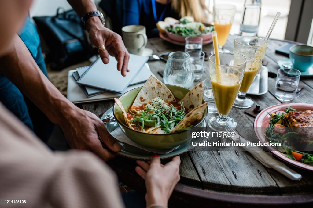Table Of Patrons With Food In Vegan Cafe