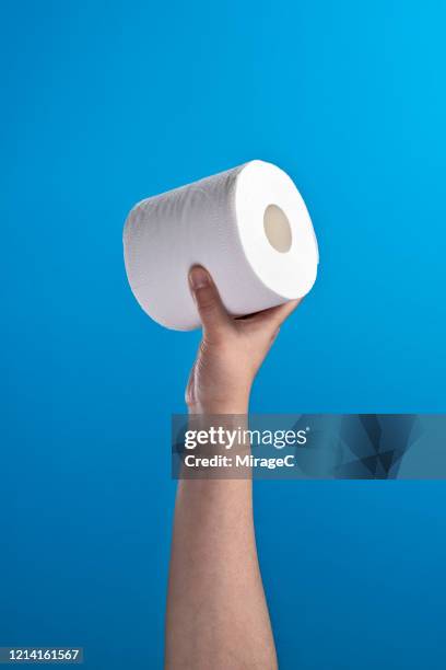 hand holding a roll of toilet paper - carta igienica foto e immagini stock