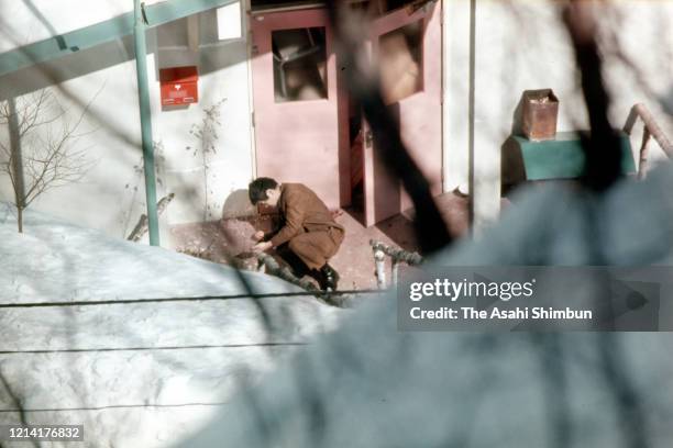 Bystander falls after being shot at the entrance of the Asama Sanso lodge, where the United Red Army members take a hostage, after sneaking through...