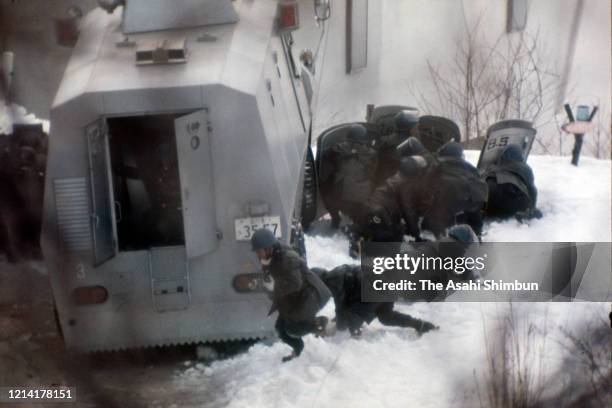 Police officers defending themselves with shields and an armed police vehicle are seen the Asama Sanso lodge as the United Red Army members take a...