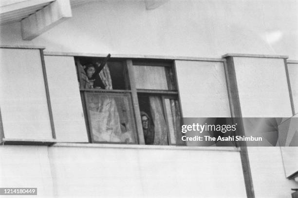 United Red Army members watch outside from the 3rd floor as police use gas bullets and water cannon as the United Red Army members take a hostage at...