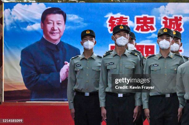 Soldiers of the People's Liberation Army's Honour Guard Battalion wear protective masks as they stand at attention in front of photo of China's...