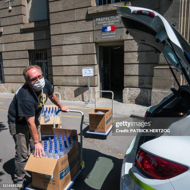 An employee of the prefecture handles boxes of hydro alcoholic gels and protective masks at a "drive-in counter" dedicated to professionnals in front...