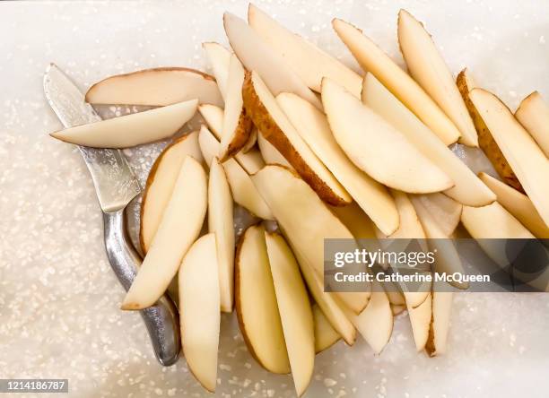 sliced potato wedges on cutting board beside knife - a potato stock pictures, royalty-free photos & images