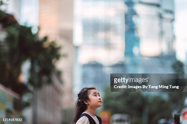 little girl looking up to sky with hope against city background - only kids at sky stockfoto's en -beelden