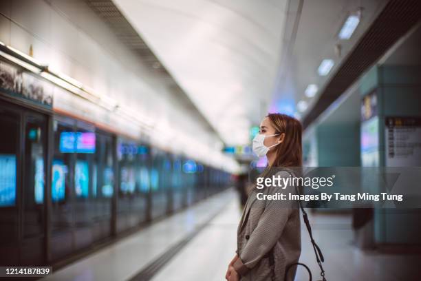 young asian woman with protective face mask commuting in the city and waiting for train in platform - metro platform stockfoto's en -beelden