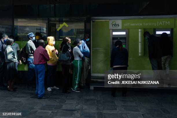 People queue for cash at an ATM which dispensed the new Zimbabwean ten-dollar notes in Harare on May 20, 2020. - The Reserve Bank of Zimbabwe...