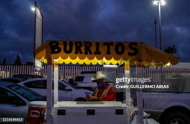 Street food vendor prepares to sell burritos to commuters waiting for the Otay Mesa Port of Entry to open, to cross to the United States from...