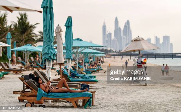 Woman uses her phone while on a lounge chair at the Jumeirah al-Naseem beach in Dubai on May 20 as COVID-19 coronavirus pandemic lockdown measures...