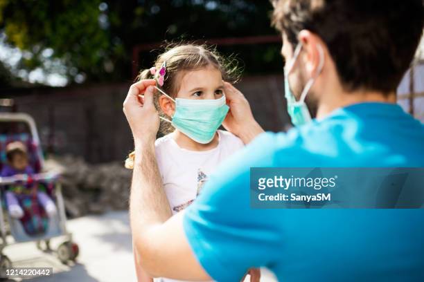 padre single che applica la maschera antinquinamento alla figlia - pandemic illness foto e immagini stock
