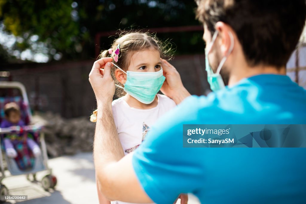 Single father applying pollution mask to his daughter