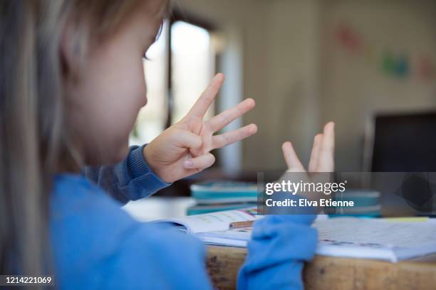 child (6-7) counting with fingers whilst doing school mathematics homework - zählen stock-fotos und bilder