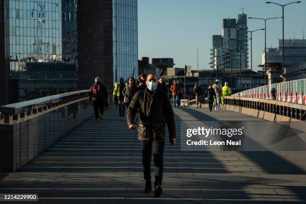 Commuter wearing a protective mask crosses London Bridge, on March 23, 2020 in London, United Kingdom. Coronavirus pandemic has spread to at least...