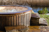 How water swirling in wooden hot tub outside in nature. Enjoying hot steaming pool on a sunny day, private spa treatment. Nobody